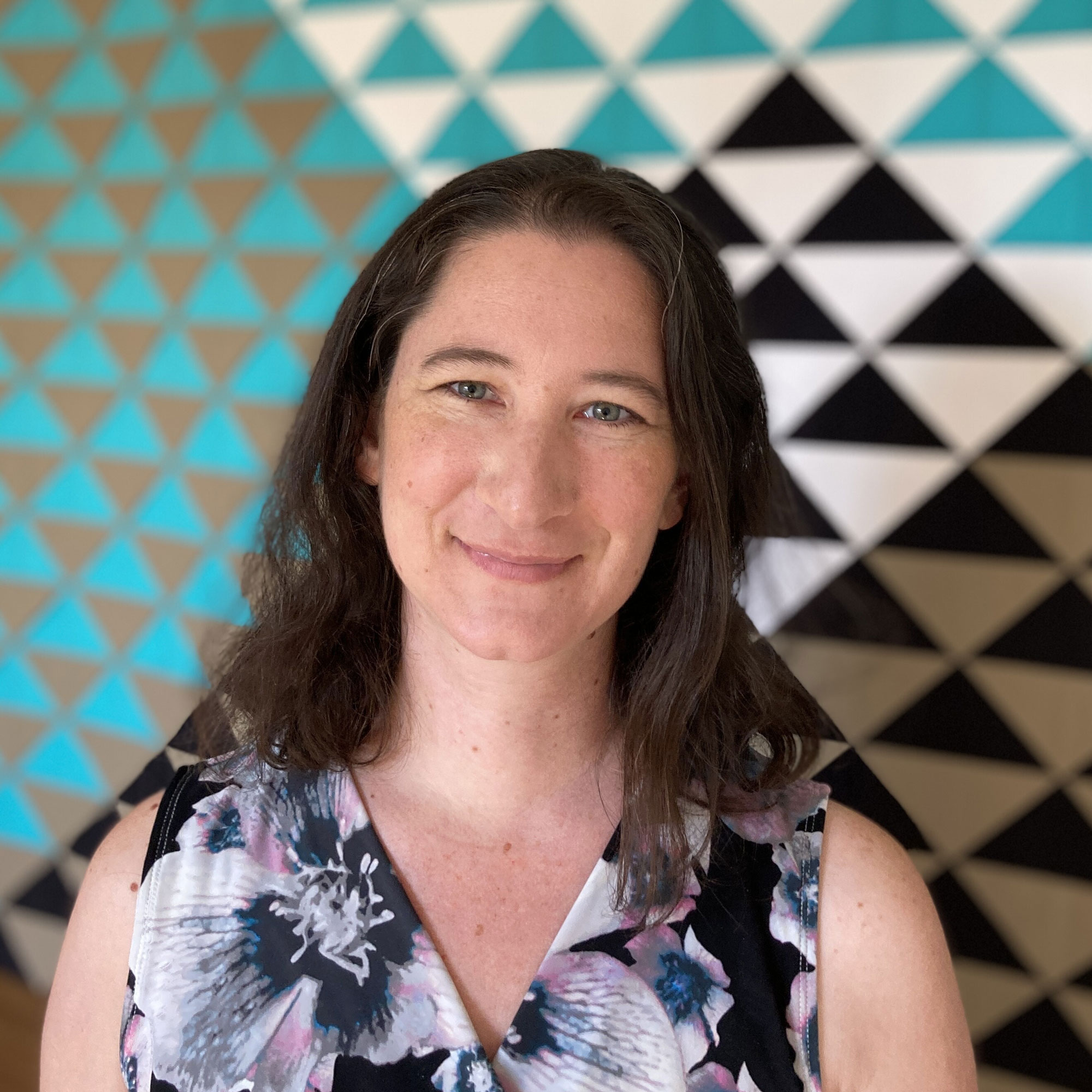 Karen Bolan in front of a green, white and black triangle quilt