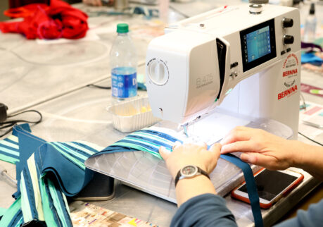 a sewing machine with hands pushing fabric through